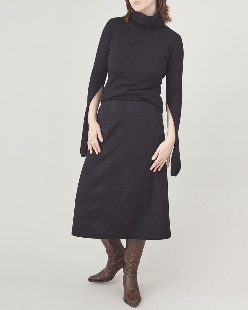 Person wearing a black dress with cape sleeves on a white background