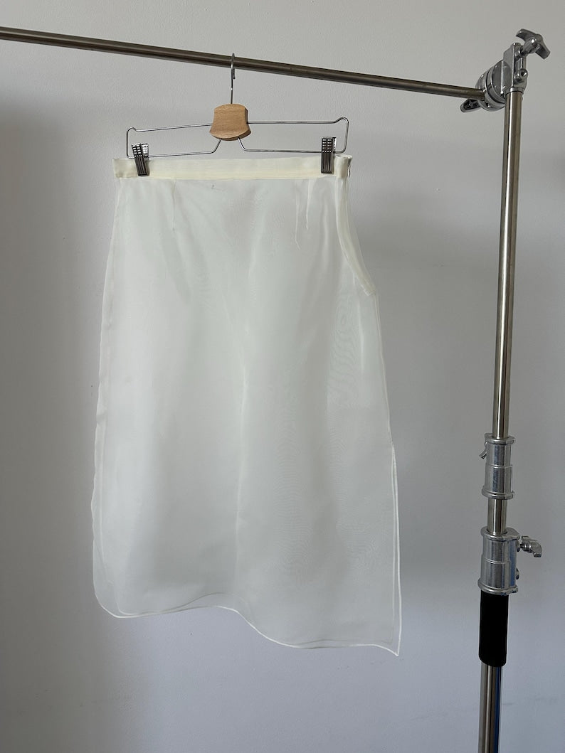 White sheer skirt hanging on a rack against a plain background