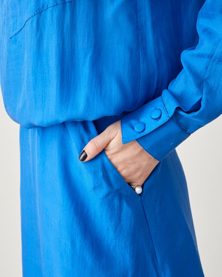 Close-up of the silk-covered sleeve buttons and side pocket on the blue midi dress.