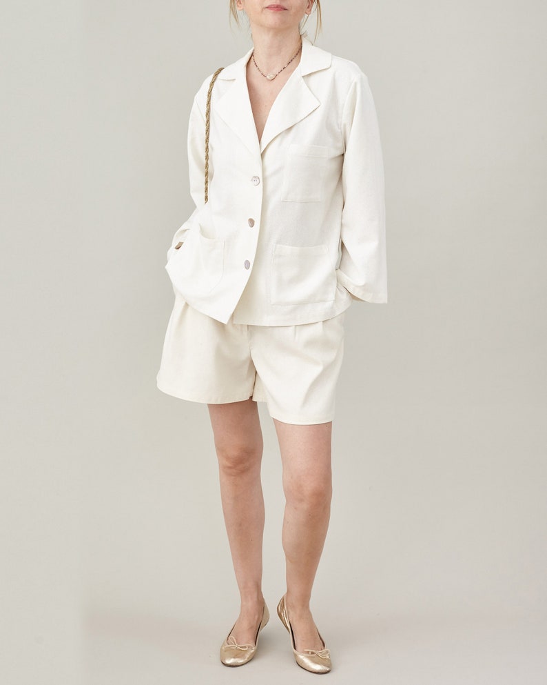 Person wearing a white suit with shorts on a plain background