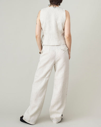 Person wearing a sleeveless beige top and wide-leg pants on a plain background