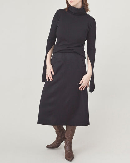 Person wearing a black dress with cape sleeves on a white background