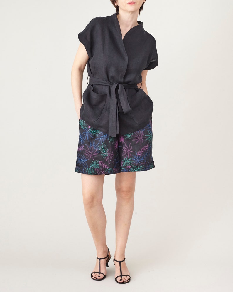 Woman wearing a black top and patterned shorts on a white background