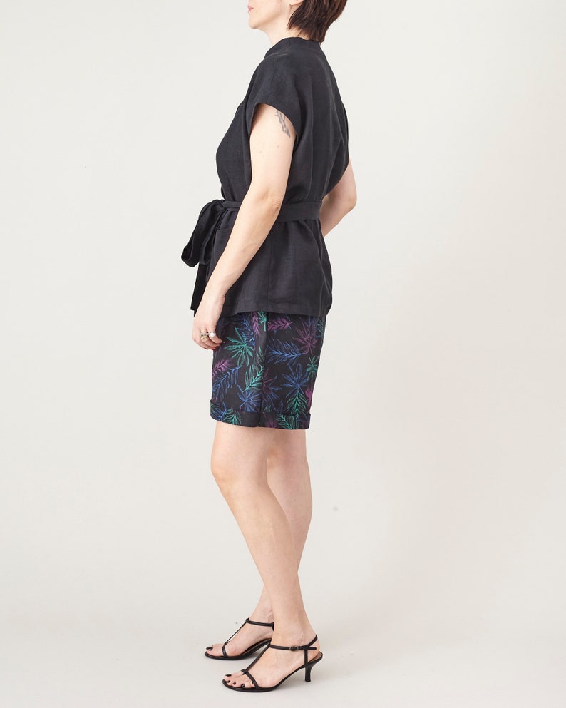 Person wearing a black top and patterned shorts on a white background