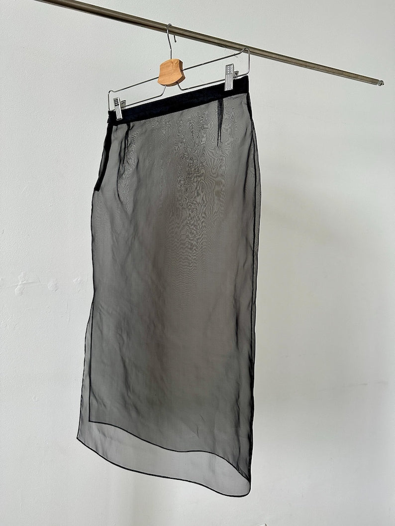 Black sheer skirt hanging on a rack against a white wall