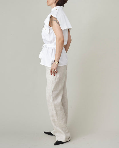 Person wearing a white blouse and beige pants on a plain background