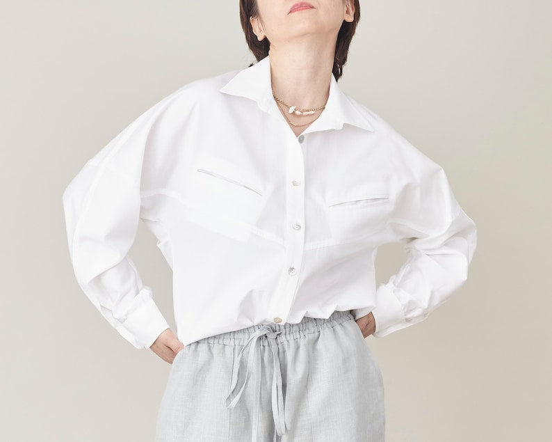 Person wearing a white shirt and light gray pants against a plain background