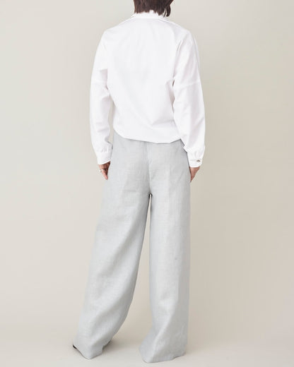 Person wearing a white shirt and light gray pants on a beige background