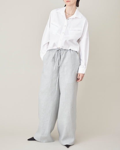 Person wearing a white shirt and light gray pants on a beige background