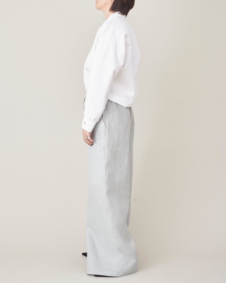 Person wearing a white shirt and light gray pants on a beige background