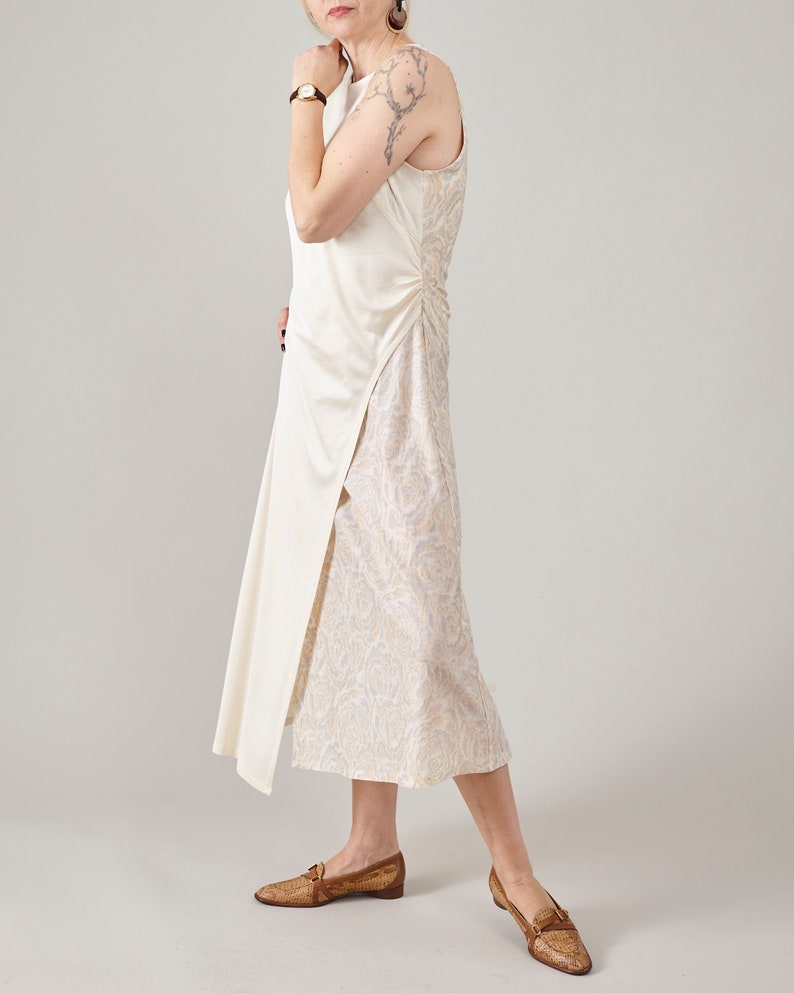 Side view of the Fine Thee asymmetric cream silk dress, showing the soft movement and interaction of the smooth matte jersey and floral jacquard panels.