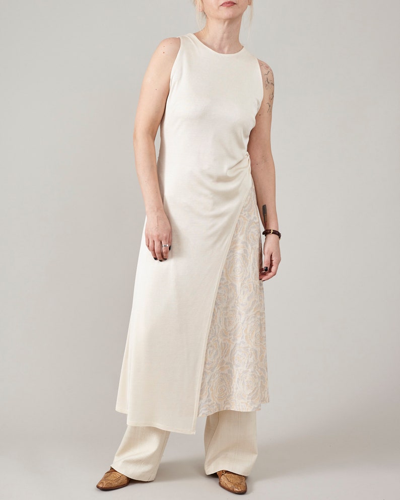 Full-length shot of Fine Thee cream asymmetric silk jersey midi dress layered over wide-leg pants, minimalist luxury summer style.
