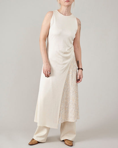 Full-length shot of Fine Thee cream asymmetric silk jersey midi dress layered over wide-leg pants, minimalist luxury summer style.