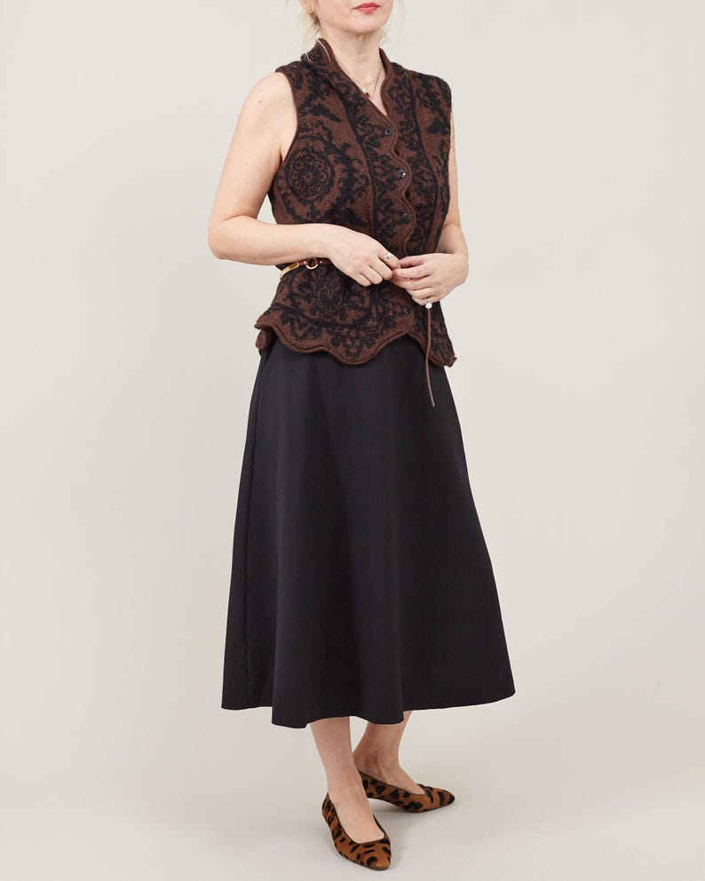 Woman wearing a sleeveless brown top and black skirt on a white background