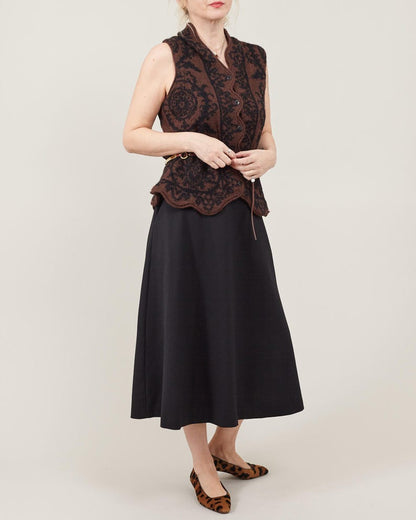 Woman wearing a sleeveless brown top and black skirt on a white background