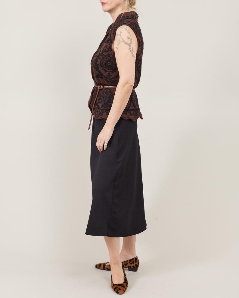 Woman wearing a patterned top and black skirt with leopard print shoes on a plain background