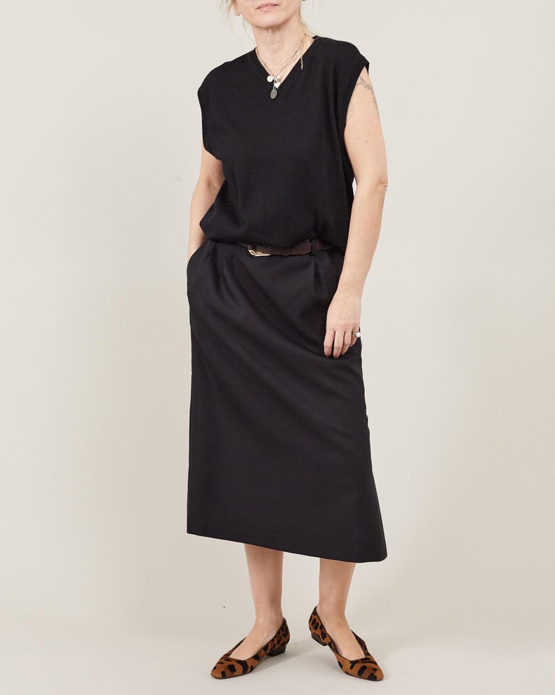 Black straight-cut wool midi skirt styled with a sweater vest and animal print shoes, elegant natural-fiber daywear outfit suitable for office or smart casual settings.