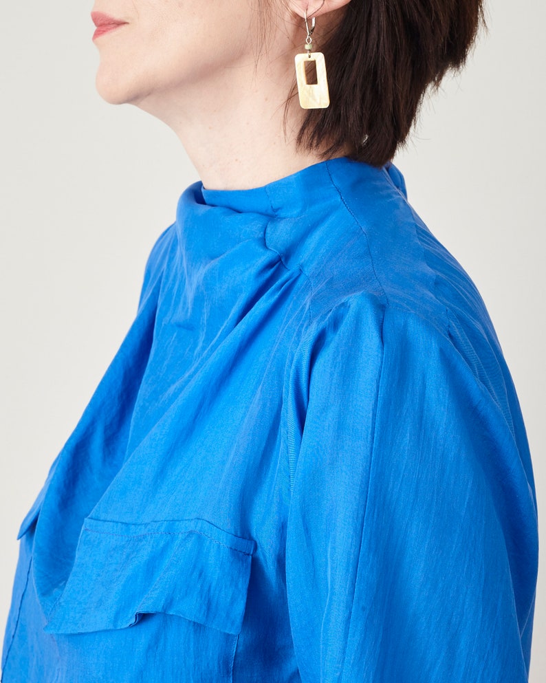 Close-up of the gathered high neckline and shoulder detail on the blue silk midi dress.