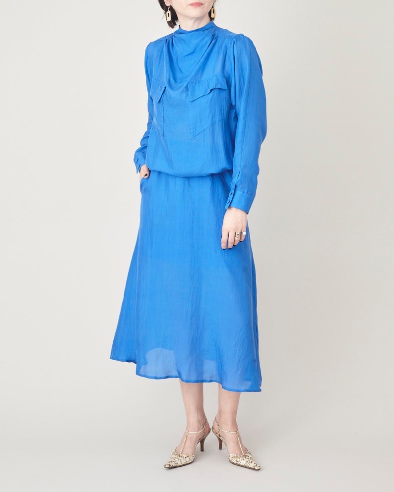 Front view of the blue silk midi dress showing its relaxed bodice and fluid skirt.