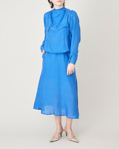 Front view of the blue silk midi dress showing its relaxed bodice and fluid skirt.