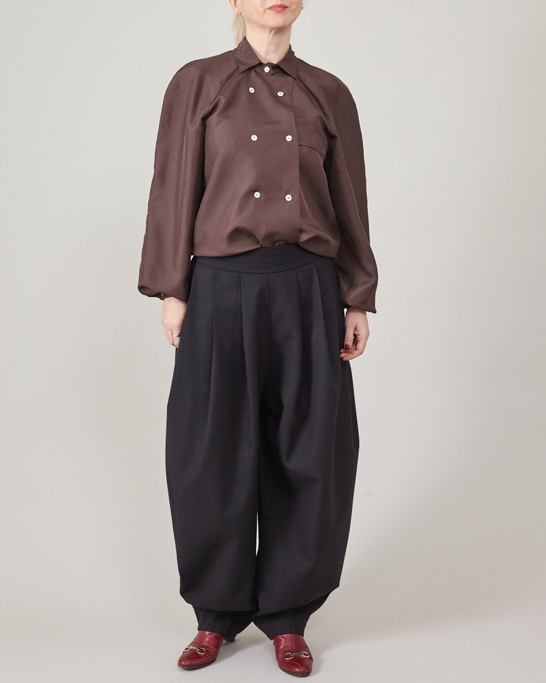 Full front view of a brown silk cape blouse with a double-breasted front, styled with black wide-leg pants.