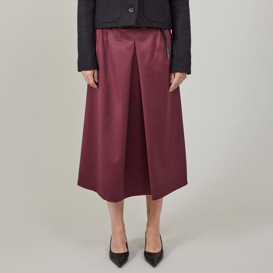 Person wearing a dark blazer and burgundy skirt on a neutral background