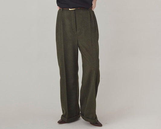 Front view of olive cashmere wide-leg pants with a high pleated waist and pressed creases, worn with a black top.