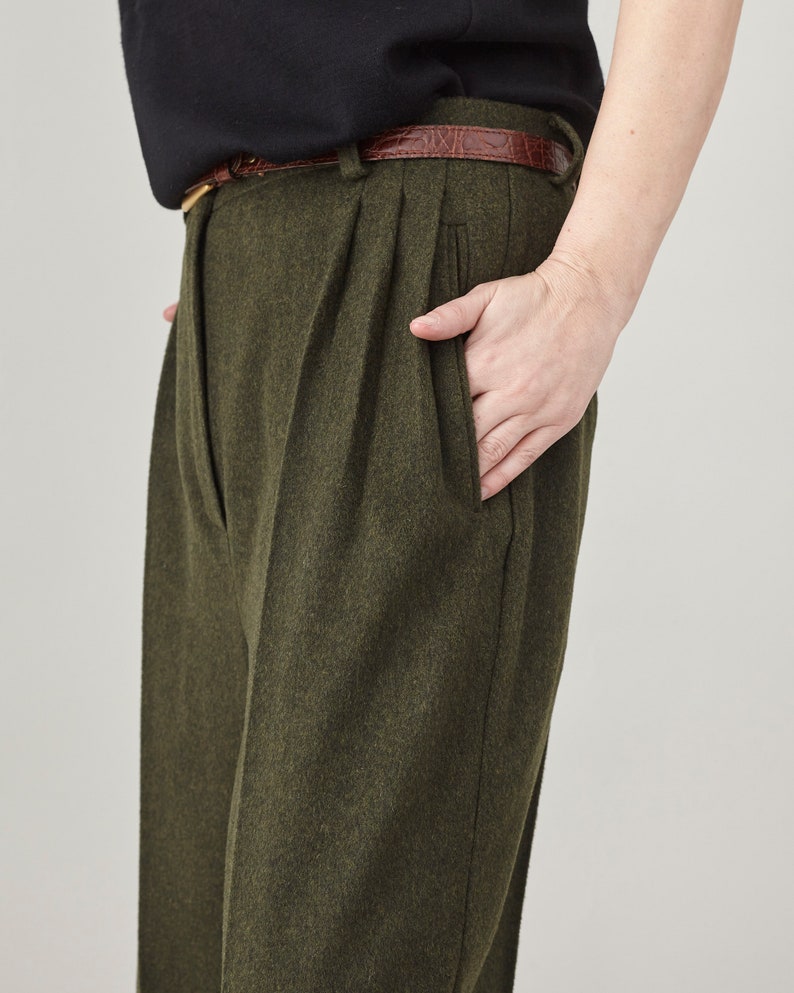 Close-up of the side pocket and pleated front on olive cashmere wide-leg pants.