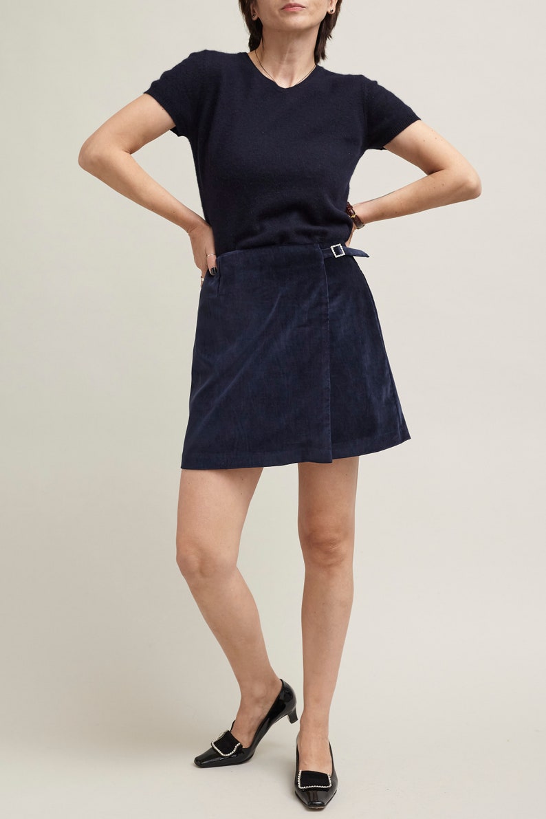 Person wearing a navy blue top and skirt on a plain background