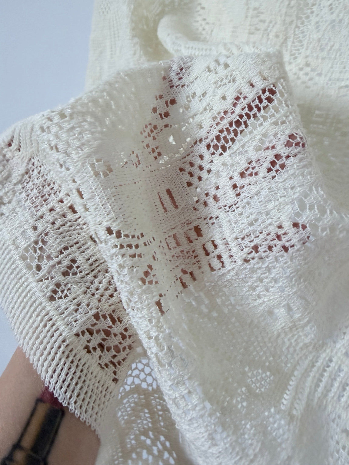 Close-up cream sheer openwork wool blend knit texture