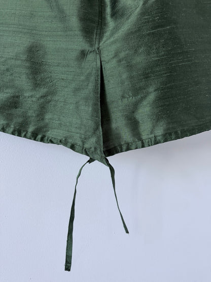 Close up of green silk skirt overlapping front slit and adjustable hem