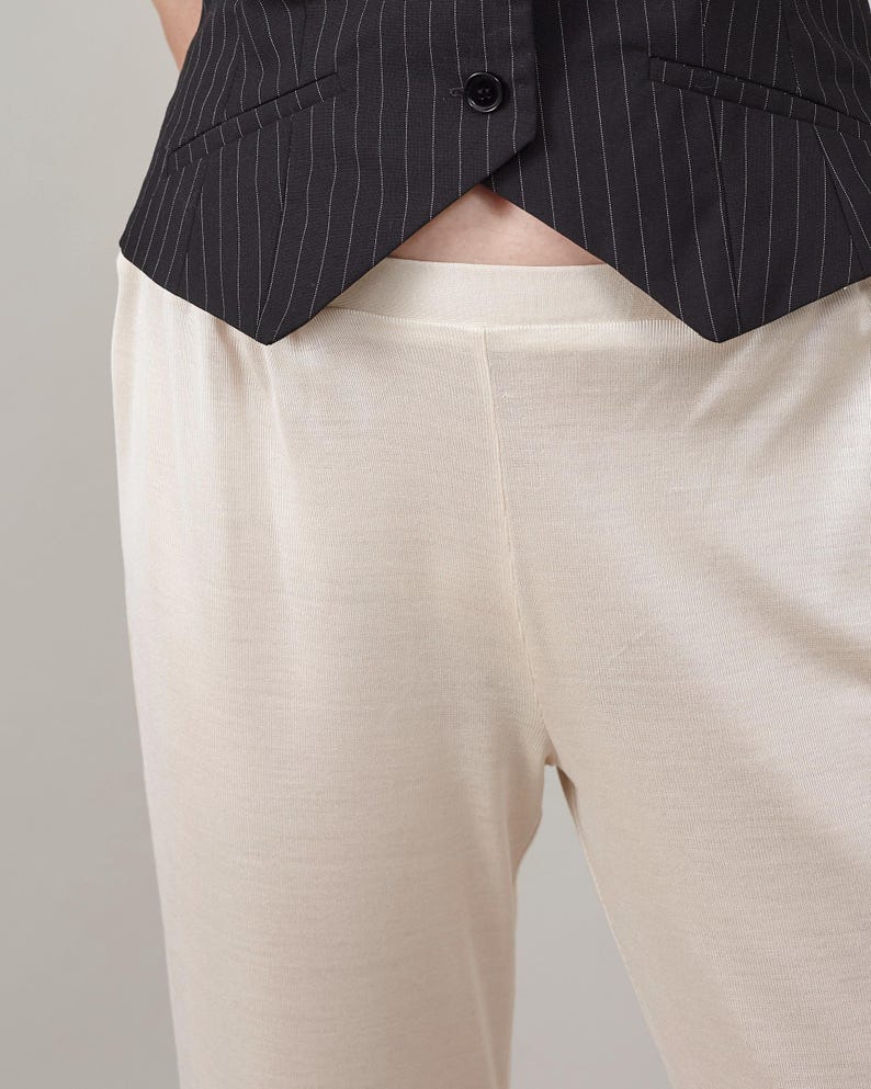 Close-up of the elastic waist and soft texture on ivory silk jersey pants.