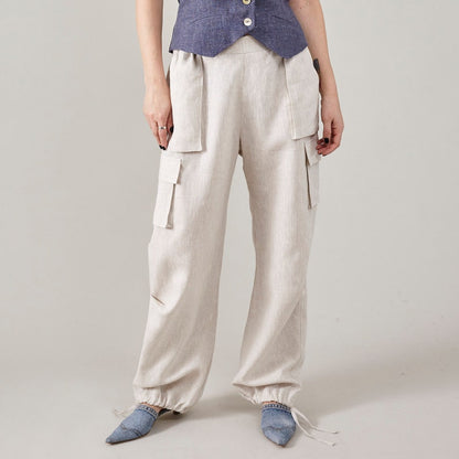 Front view of off-white linen cargo pants with patch pockets and adjustable drawstring hems.
