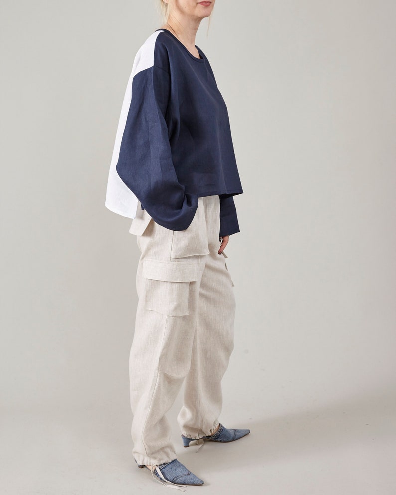 Side view of off-white linen cargo pants styled with an oversized navy and white top.
