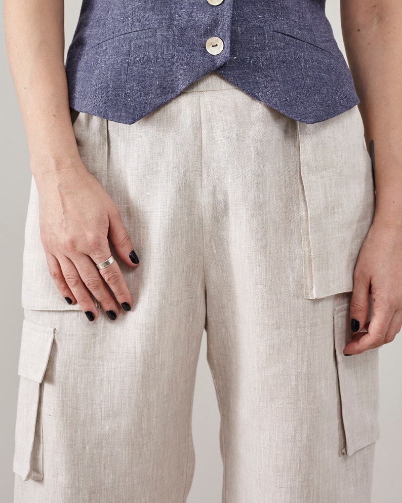Close-up of the patch and flap pockets on off-white linen cargo pants.