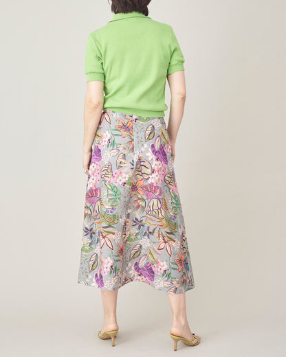 Person wearing a green top and floral skirt on a plain background