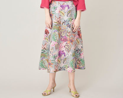 Woman wearing a colorful floral skirt and pink top on a plain background