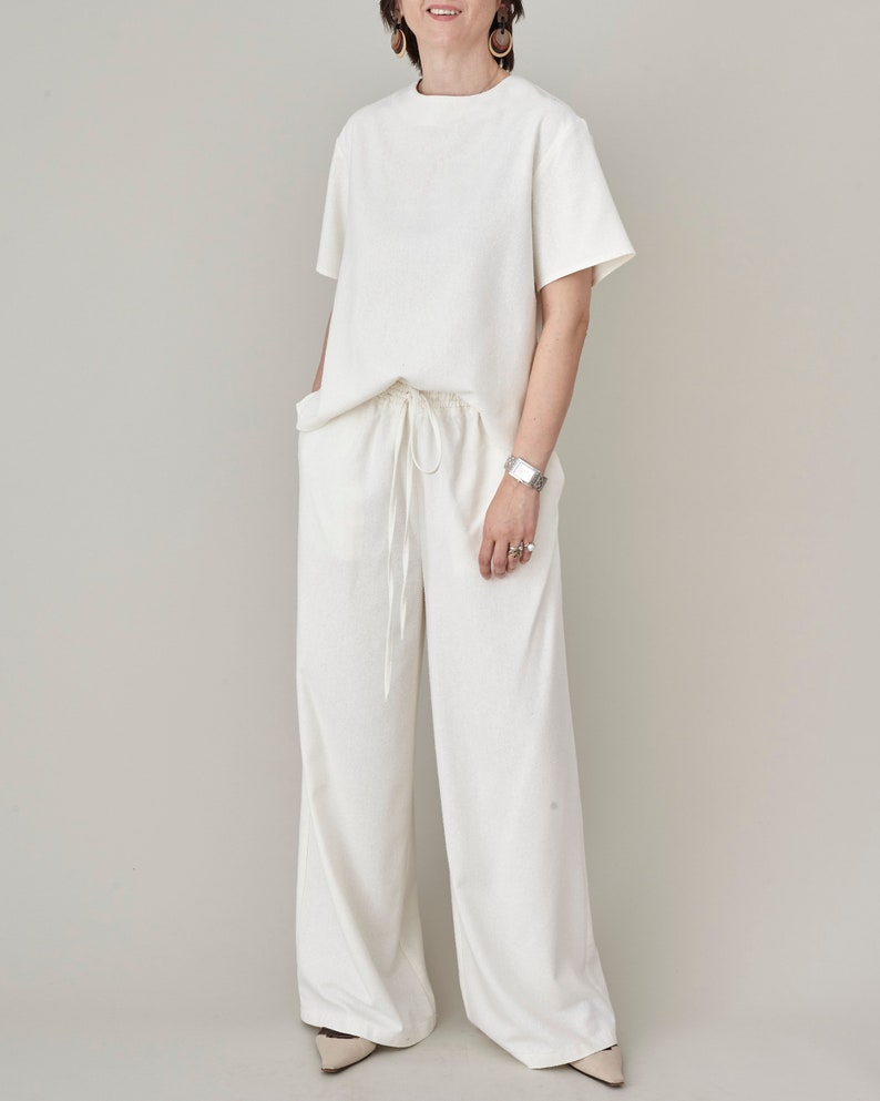 Full length casual pose of model wearing the natural ivory raw silk wide-leg pants and matching top by Fine Thee