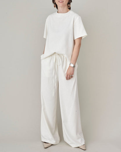 Full length casual pose of model wearing the natural ivory raw silk wide-leg pants and matching top by Fine Thee
