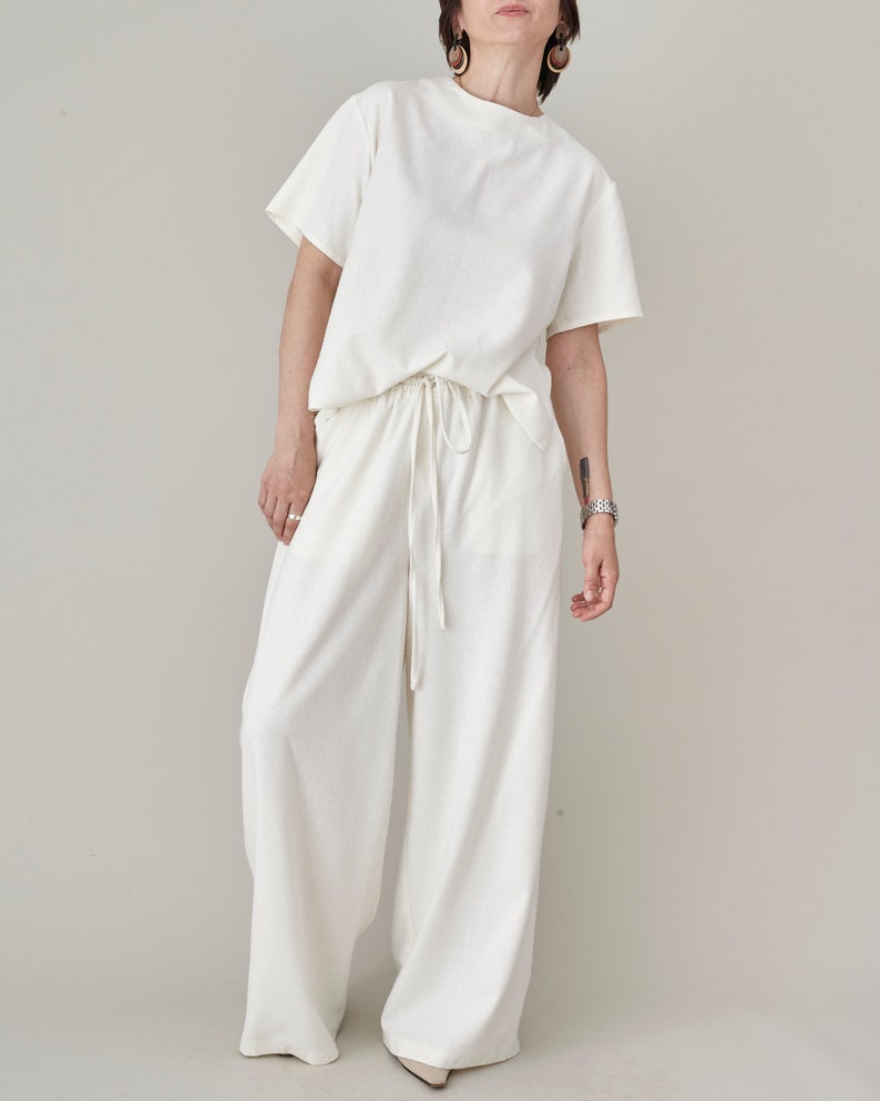 Full length view of a monochromatic raw silk set featuring ivory wide-leg trousers and matching t-shirt by Fine Thee