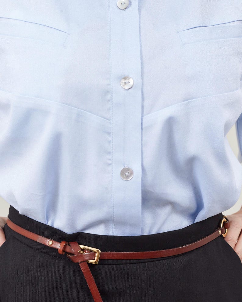 Light blue shirt with a brown belt and black pants