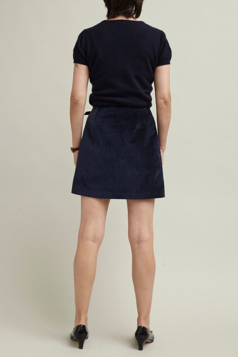 Person wearing a navy blue top and skirt on a plain background