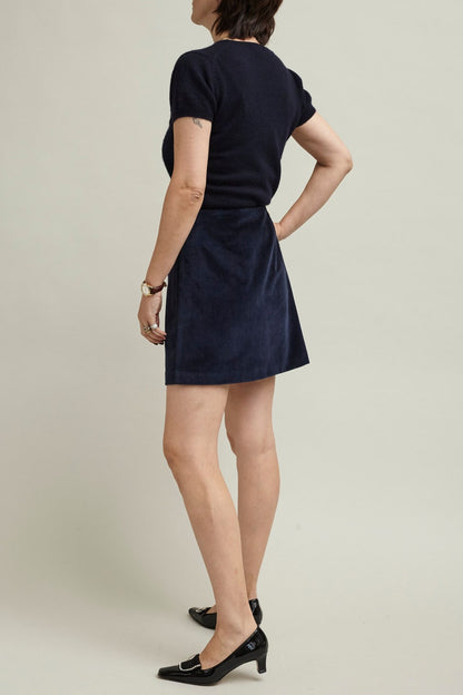 Person wearing a navy short sleeve knit top and a navy mini skirt in a studio