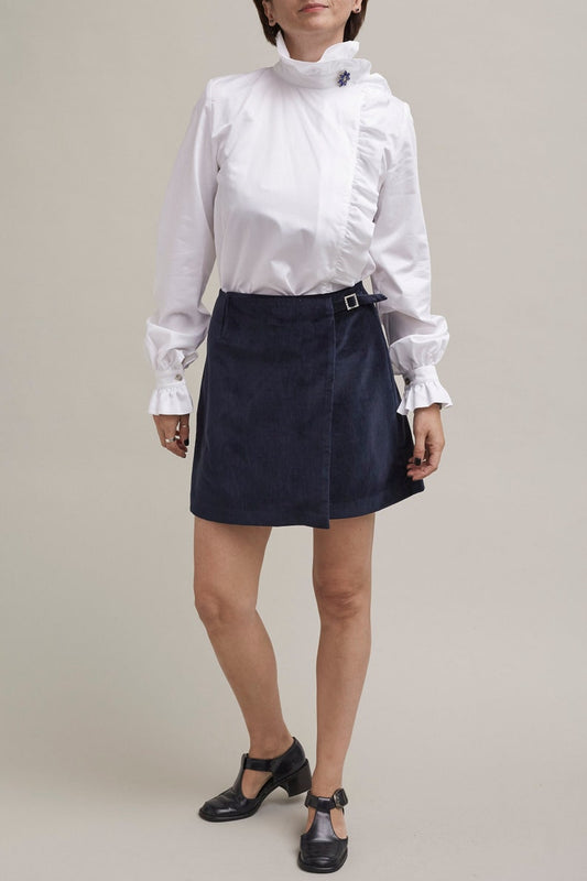 Person wearing a white blouse and navy skirt on a plain background