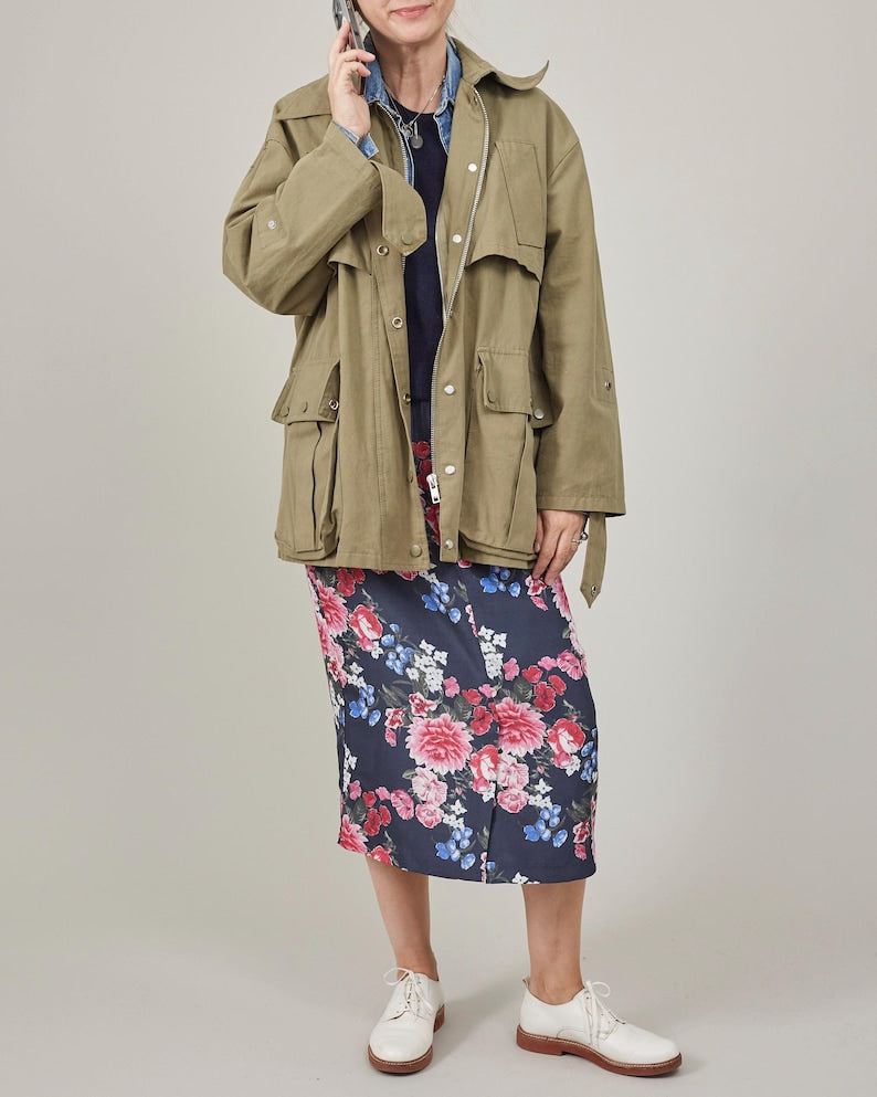 Person wearing a green jacket and floral skirt on a plain background