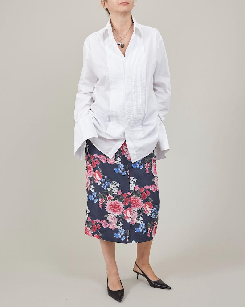 Person wearing a white blouse and floral skirt on a plain background