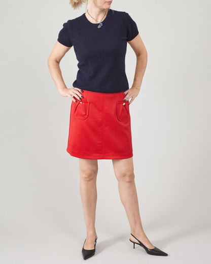 Person wearing a navy top and red skirt on a plain background