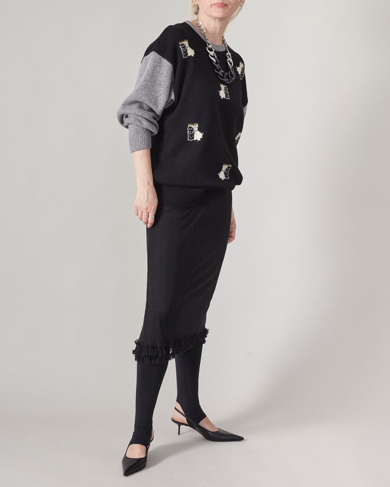 Person wearing a black sheer skirt layered over black opaque tights and an oversized fluffy sweater