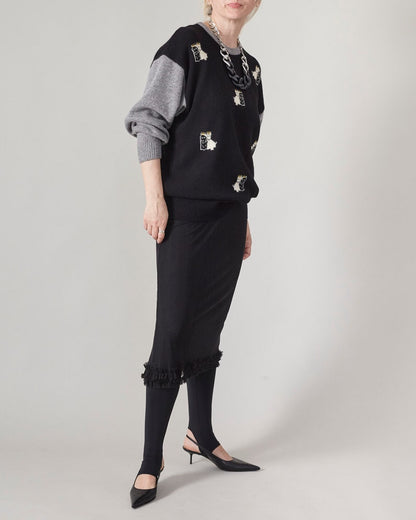 Person wearing a black sheer skirt layered over black opaque tights and an oversized fluffy sweater