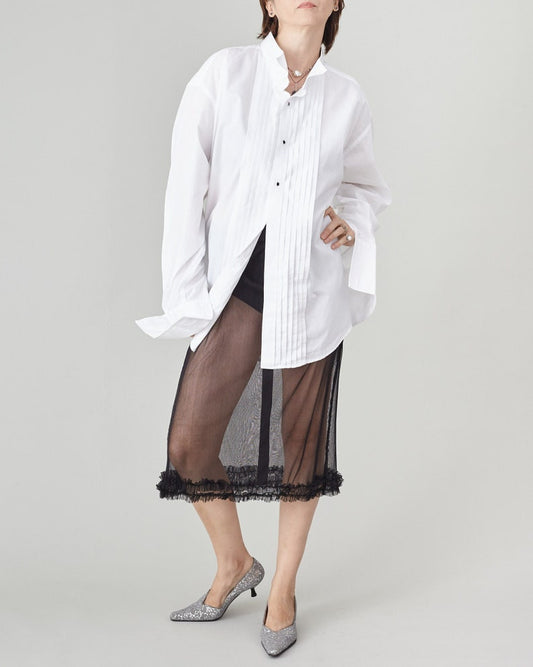 Person wearing a white shirt and black sheer skirt on a plain background